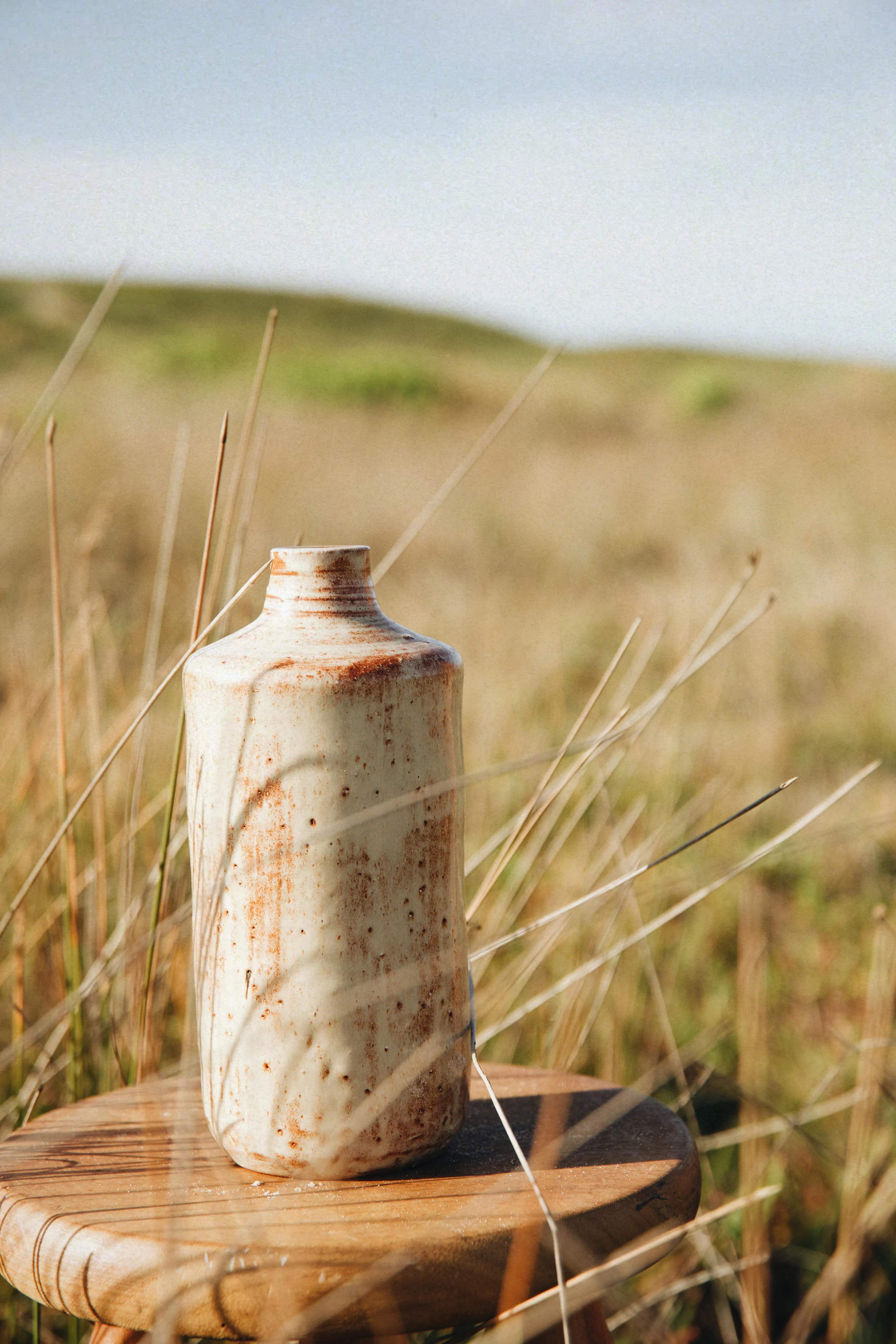 The tall bottle of the Dunes Trio alone on the stool, dunes in the distance