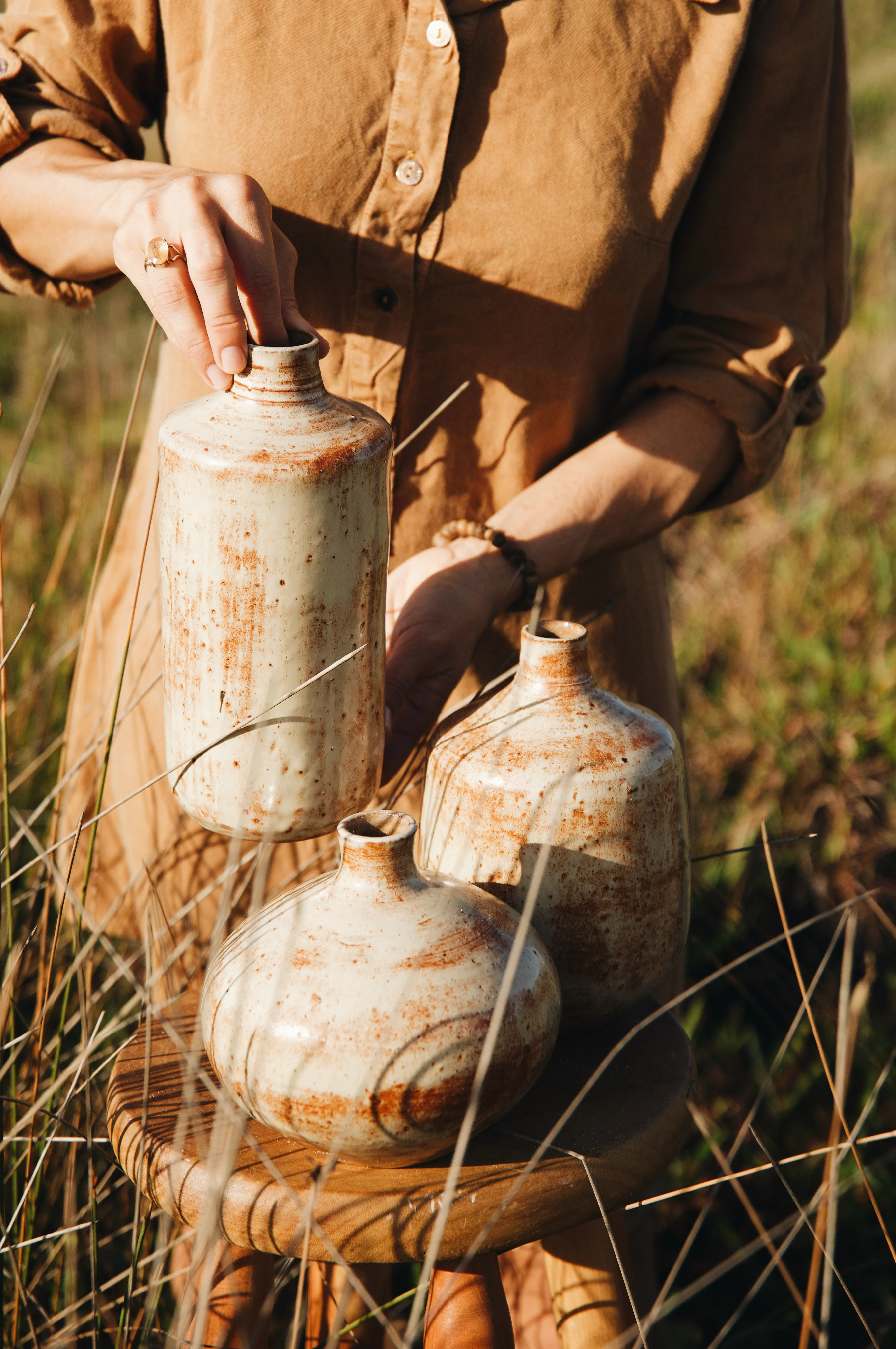 Ramoni holding the tall bottle of the Dunes Trio above the other two vessels