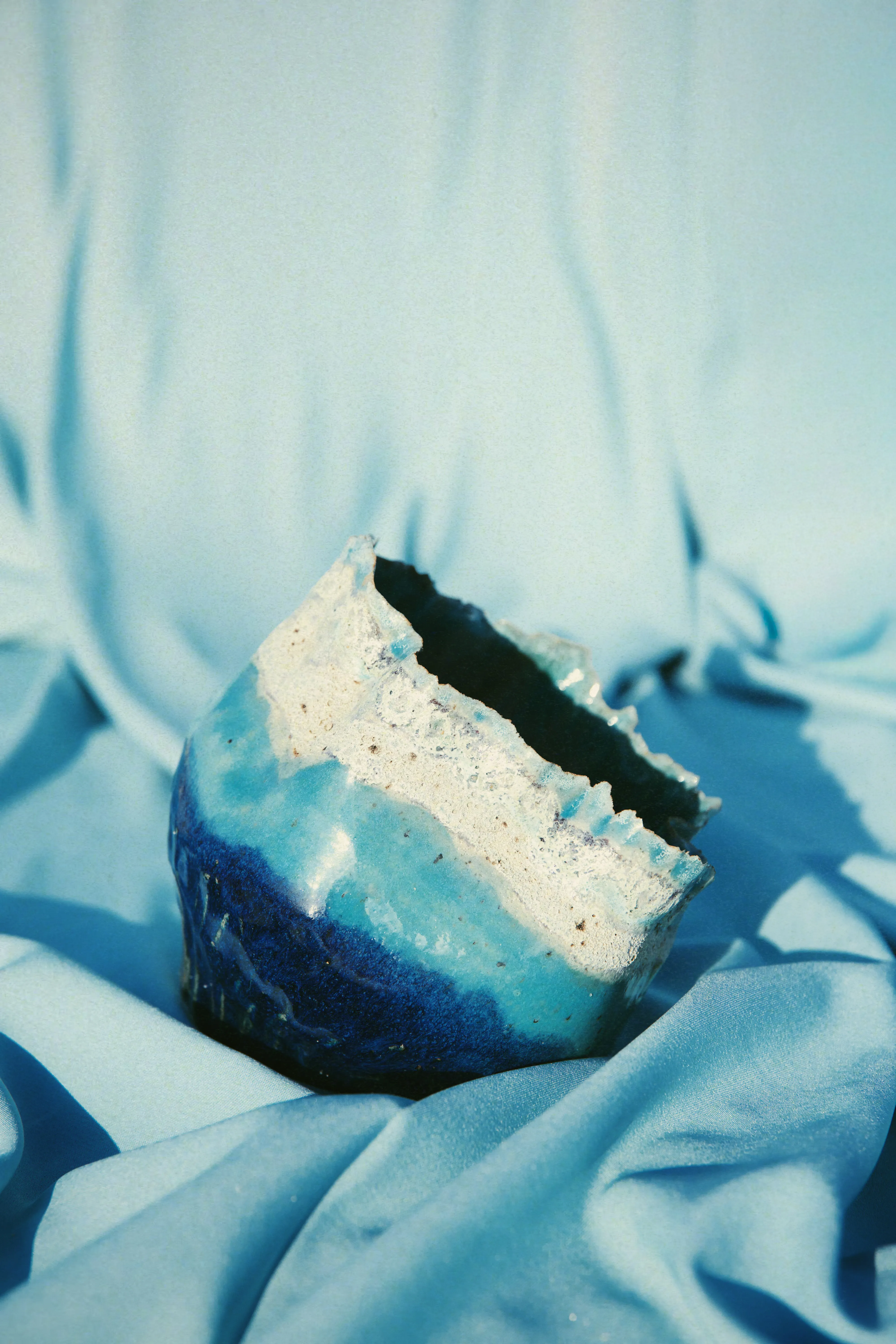 Tigela Mar #01 de lado sobre tecido azul, com a faixa de espuma branca cristalizada na borda