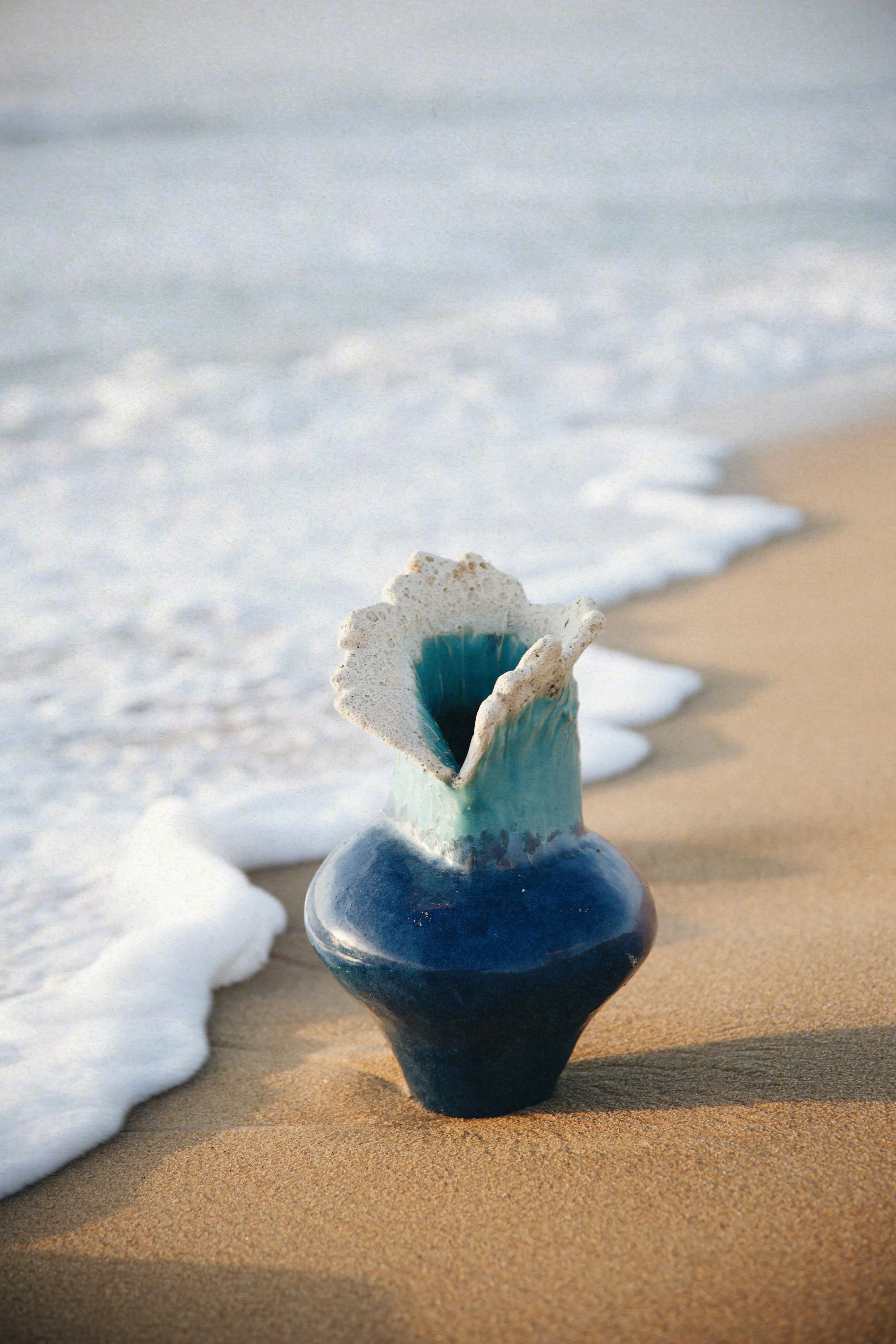 Vaso da Série Mar na areia da praia com a espuma da onda ao fundo