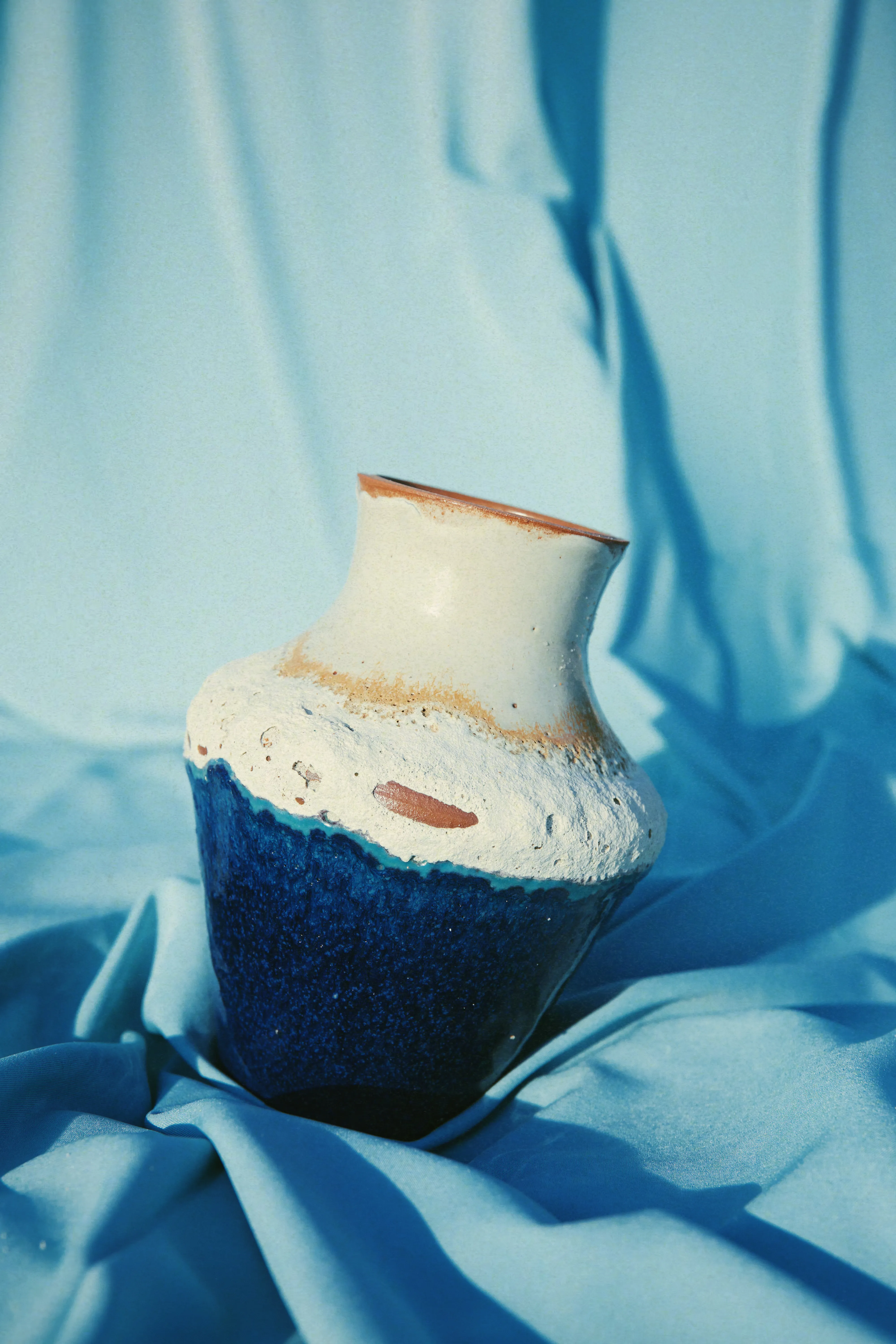 Vaso Mar #05 sobre tecido azul, gargalo claro inclinado e corpo em azul profundo